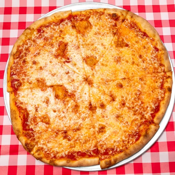 A whole cheese pizza, cut into slices, on a metal tray over a red and white checkered tablecloth.